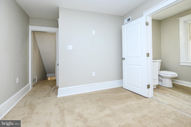 unfurnished bedroom with carpet floors, visible vents, baseboards, and connected bathroom