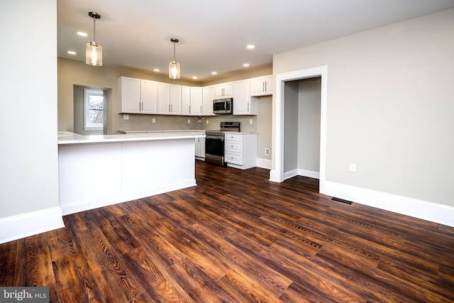 kitchen with white cabinets, dark wood-style flooring, a peninsula, stainless steel appliances, and light countertops