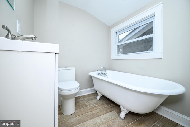 full bath featuring toilet, a soaking tub, wood tiled floor, and vaulted ceiling