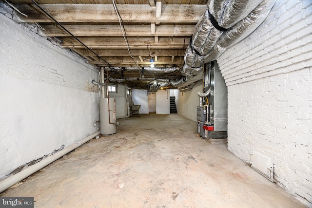 basement featuring gas water heater, brick wall, and heating unit