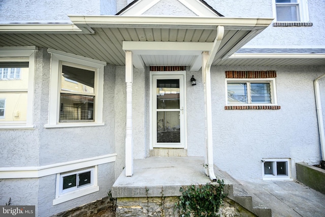 property entrance featuring a porch and stucco siding