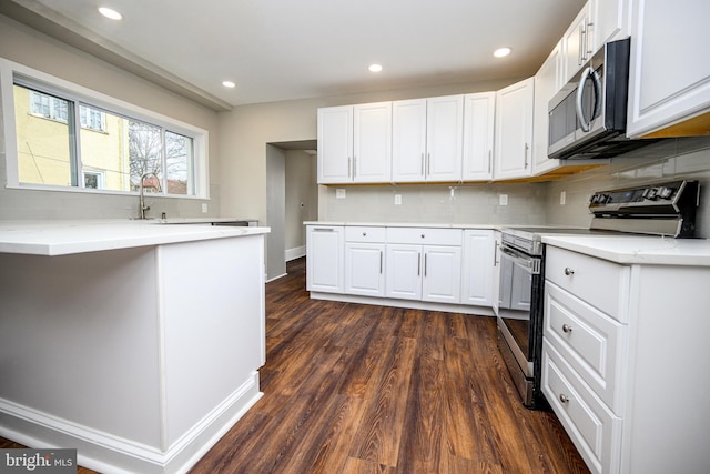 kitchen featuring white cabinets, dark wood-style floors, appliances with stainless steel finishes, backsplash, and recessed lighting