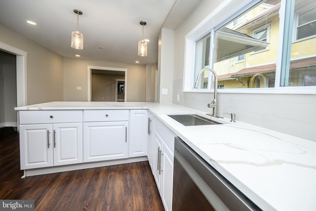 kitchen with a peninsula, dark wood-type flooring, a sink, white cabinetry, and light stone countertops