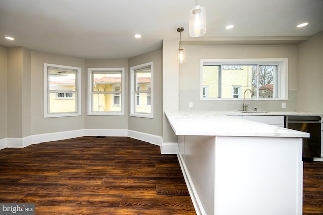 kitchen featuring dark wood-style floors, light stone counters, recessed lighting, a peninsula, and baseboards