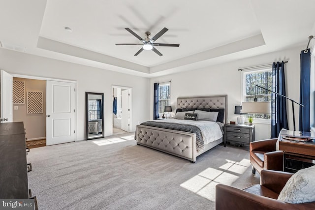 bedroom with a tray ceiling, multiple windows, carpet, and a ceiling fan