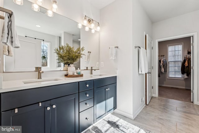 bathroom featuring double vanity, baseboards, and a sink