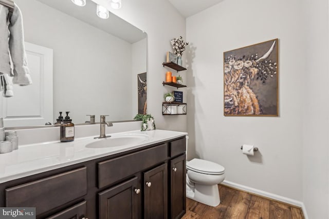 bathroom with baseboards, vanity, toilet, and wood finished floors