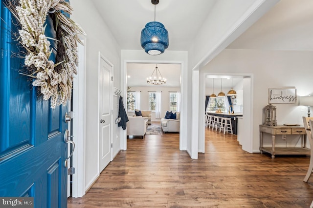 foyer entrance with an inviting chandelier and wood finished floors