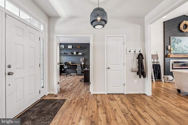 foyer entrance with a fireplace, baseboards, and wood finished floors