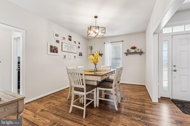 dining room featuring a chandelier, baseboards, and wood finished floors