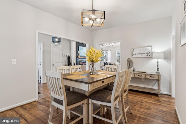 dining area featuring baseboards, an inviting chandelier, and wood finished floors