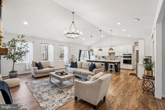 living area with high vaulted ceiling, recessed lighting, hardwood / wood-style floors, and an inviting chandelier