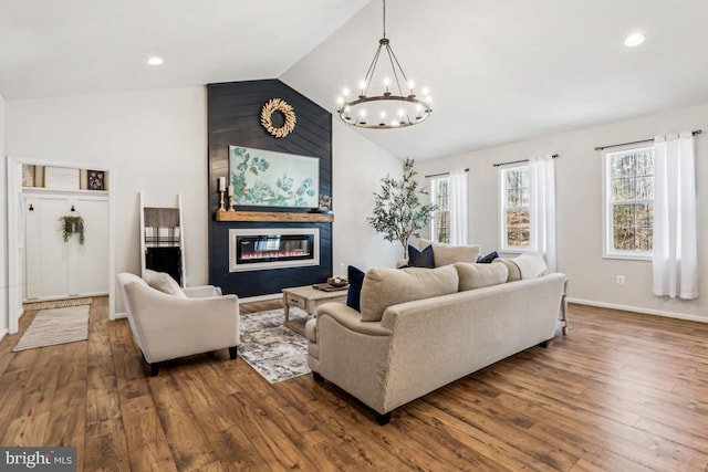 living room featuring wood finished floors, an inviting chandelier, vaulted ceiling, a fireplace, and recessed lighting