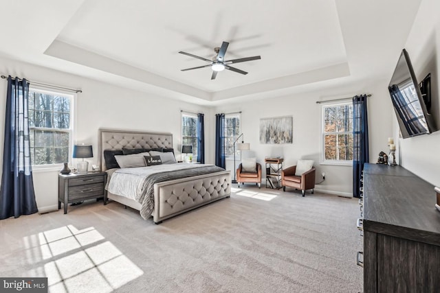 bedroom with light carpet, ceiling fan, baseboards, and a raised ceiling