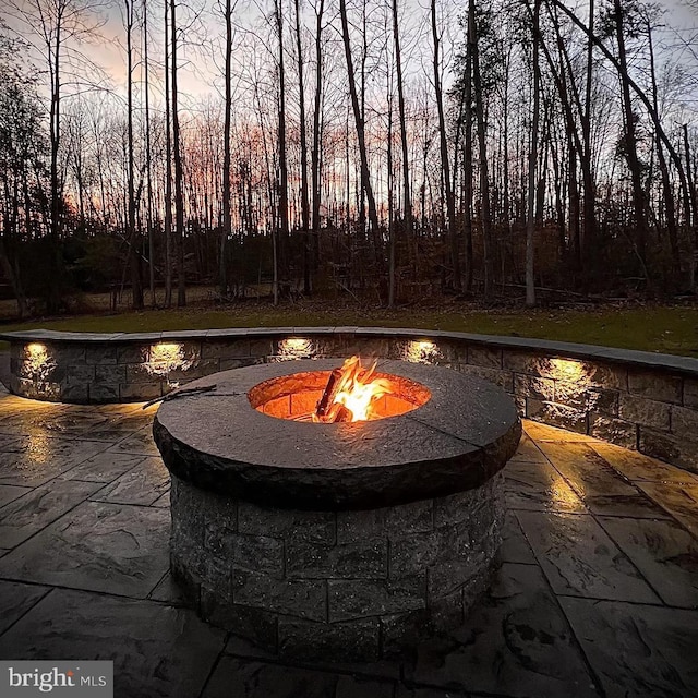 pool at dusk with a patio and a fire pit