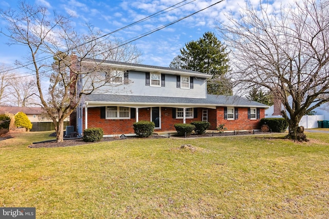 view of front of property with a front lawn, fence, and brick siding