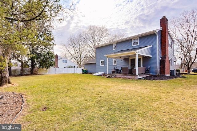 rear view of property with central air condition unit, a yard, fence, and a chimney