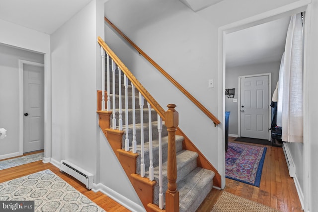 stairs with a baseboard radiator, a baseboard heating unit, baseboards, and hardwood / wood-style floors