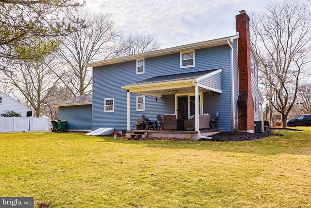 back of property with a lawn, a chimney, and fence