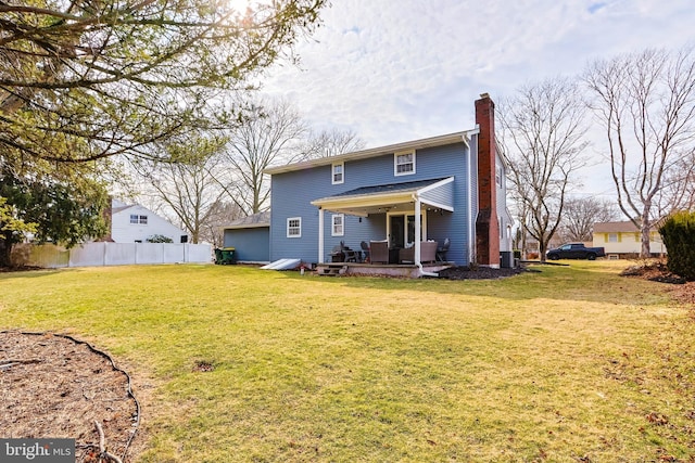 rear view of house with fence, a lawn, and a chimney