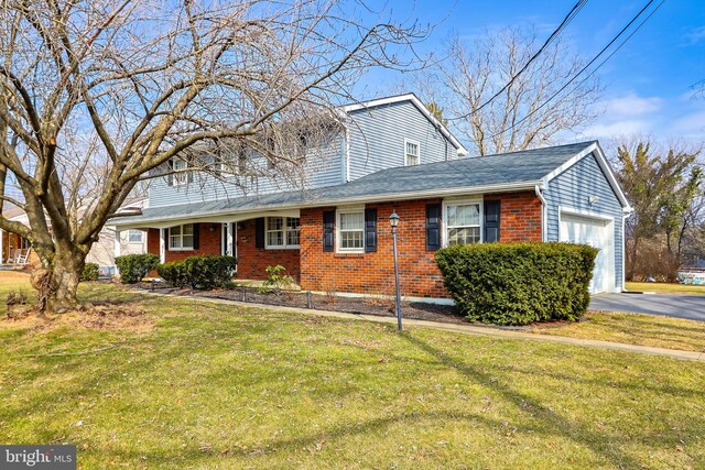 view of front of home featuring a front lawn, aphalt driveway, a shingled roof, a garage, and brick siding