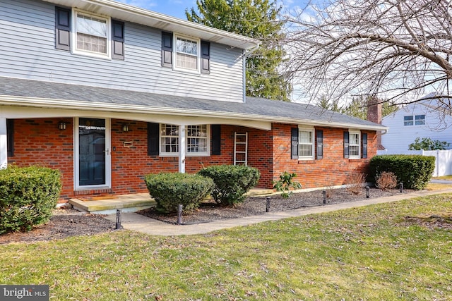 traditional-style house featuring brick siding, a porch, a front yard, and a shingled roof