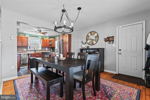 dining area with ceiling fan with notable chandelier, wood finished floors, and baseboards