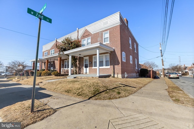 view of property featuring covered porch and brick siding