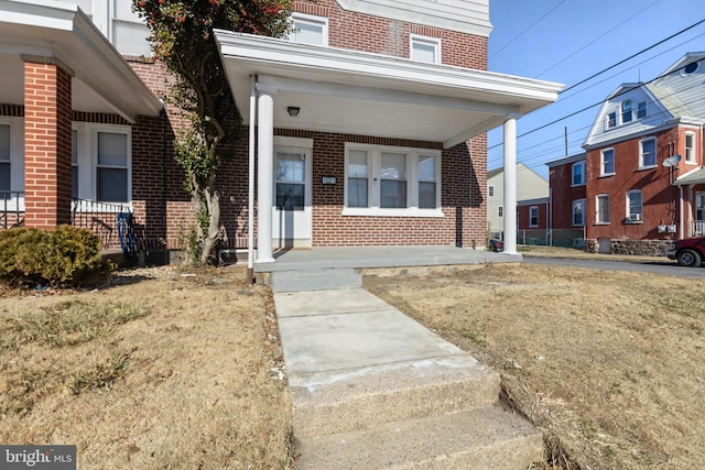 property entrance featuring covered porch and brick siding