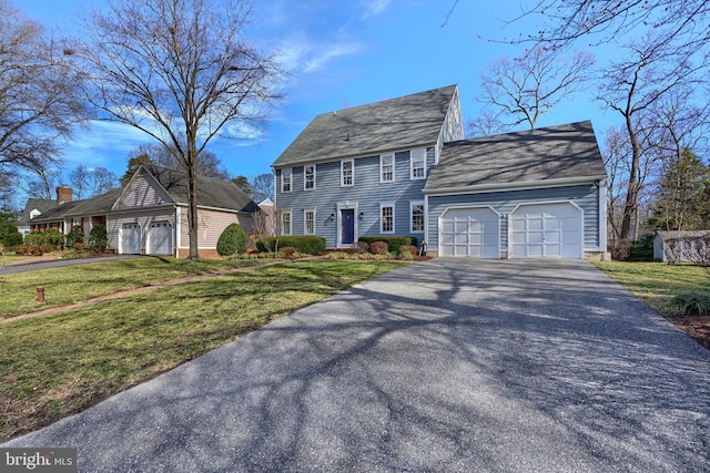 colonial home featuring a front lawn, roof with shingles, aphalt driveway, and an attached garage