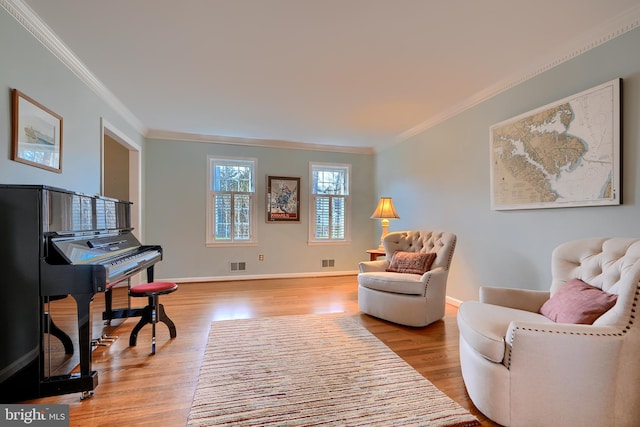 sitting room featuring crown molding, wood finished floors, visible vents, and baseboards