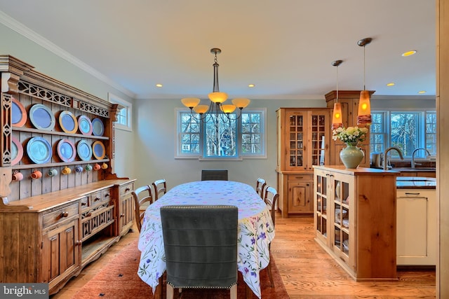 dining room with a healthy amount of sunlight, light wood-type flooring, and ornamental molding