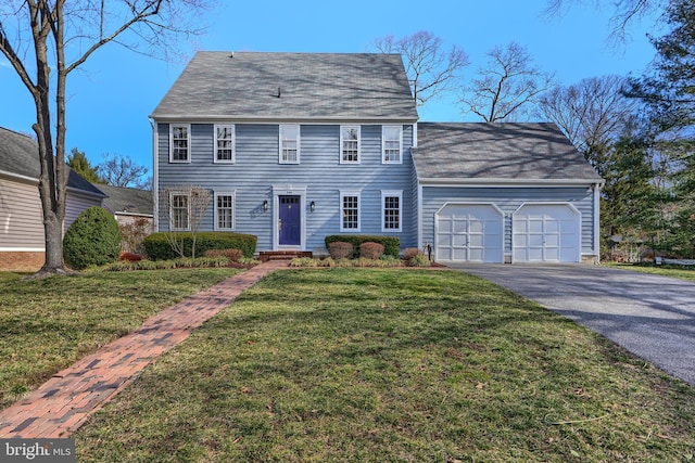 colonial home featuring driveway, a front yard, and an attached garage