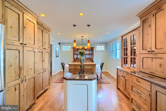 kitchen featuring dark countertops, light wood-style flooring, a kitchen island, and ornamental molding