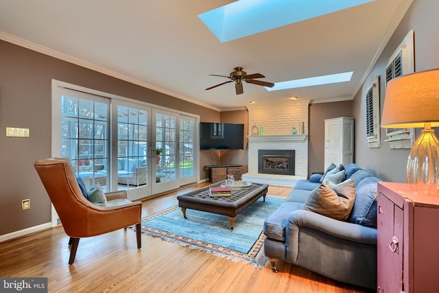 living area featuring a brick fireplace, a skylight, wood finished floors, and ornamental molding