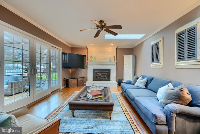 living room featuring a fireplace, crown molding, wood finished floors, and french doors