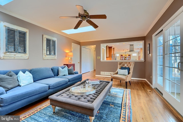 living room featuring light wood finished floors, visible vents, ceiling fan, baseboards, and ornamental molding