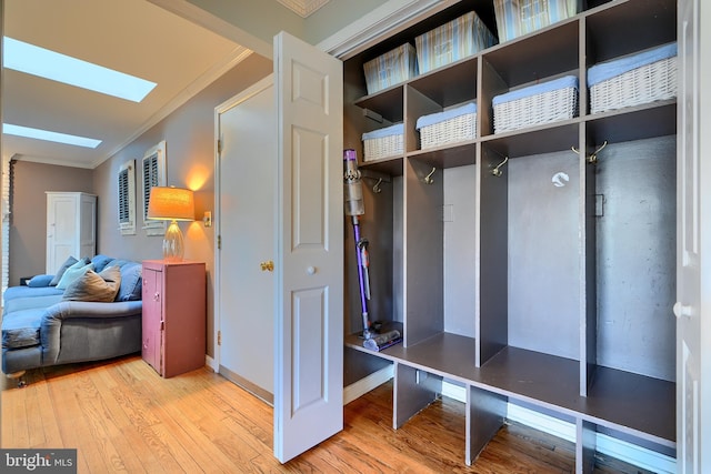 mudroom with crown molding, a skylight, and light wood-style floors