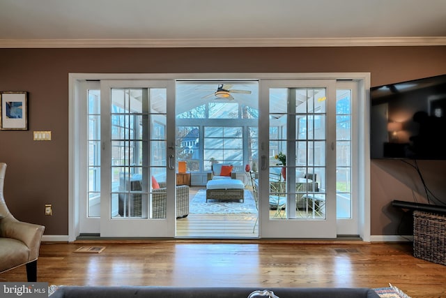 doorway featuring visible vents, ornamental molding, baseboards, and wood finished floors