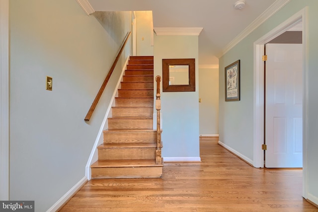 staircase featuring crown molding, baseboards, and wood finished floors