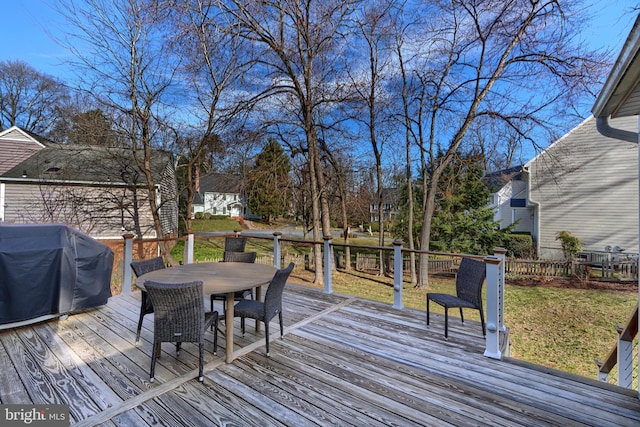 wooden terrace featuring outdoor dining area, a lawn, and a grill