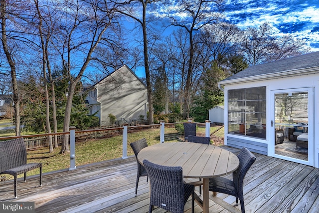 wooden terrace with outdoor dining area and an outdoor structure