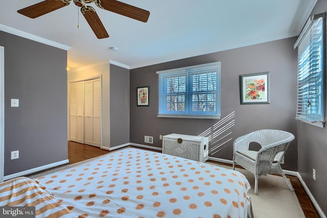 bedroom featuring multiple windows, wood finished floors, baseboards, and ornamental molding