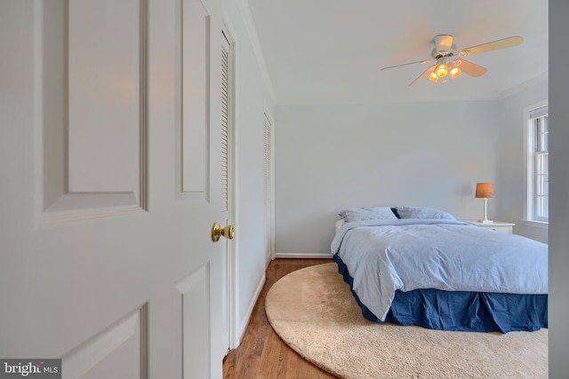 bedroom featuring crown molding, wood finished floors, baseboards, and ceiling fan