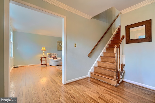 stairway featuring baseboards, wood finished floors, and crown molding