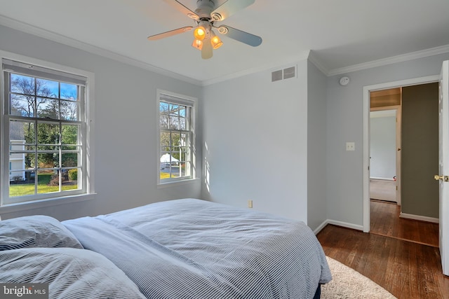 bedroom with visible vents, crown molding, baseboards, and wood finished floors