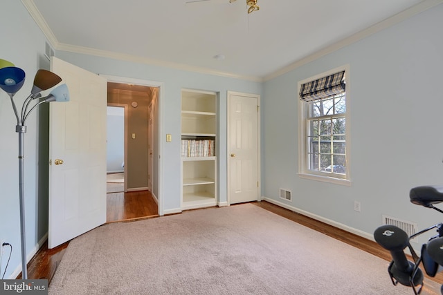 exercise area with built in shelves, visible vents, baseboards, and ornamental molding