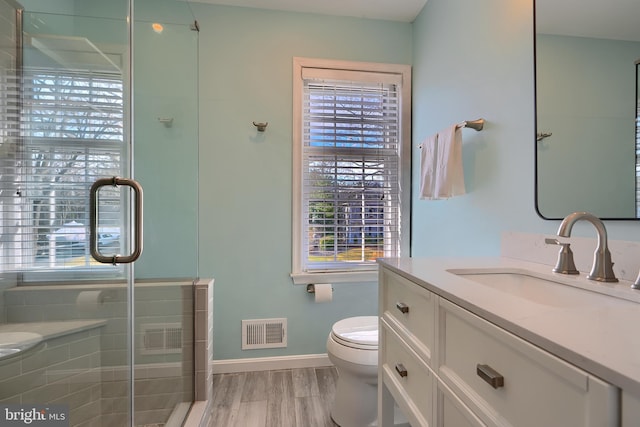 bathroom with visible vents, toilet, wood finished floors, and a shower stall