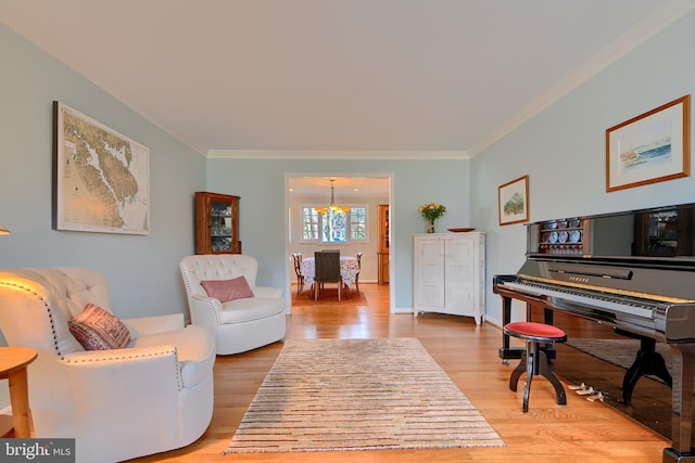 sitting room with light wood-type flooring, a notable chandelier, and crown molding