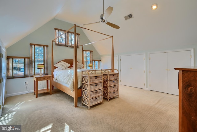 bedroom with vaulted ceiling, visible vents, two closets, and light carpet